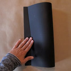Folding black card stock paper in half vertically.