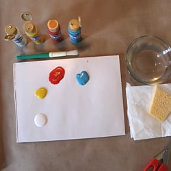 Paint palate consisting of white, yellow, red, and blue paint, along with paint brush, water, sponge, and scissors.