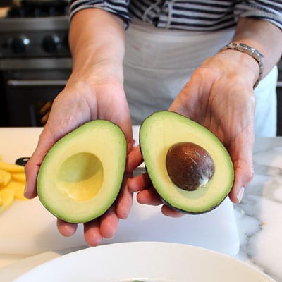 Two halves of an avocado, seed intact.